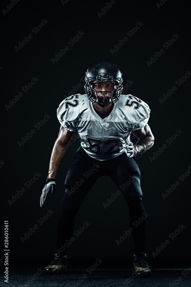 American football sportsman player in helmet on black background. Sport and motivation. Team sports. American football sportsman player in helmet on black background. Sport and motivation. Team sports.