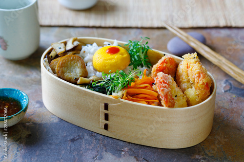 Japanese bento box with tempura prawns, rice and vegetables photo