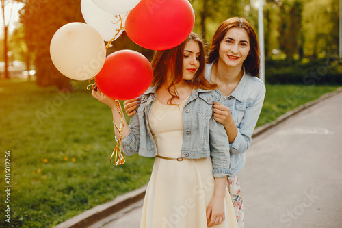 Canvastavla two young and bright girls spend their time in the summer park with balloons