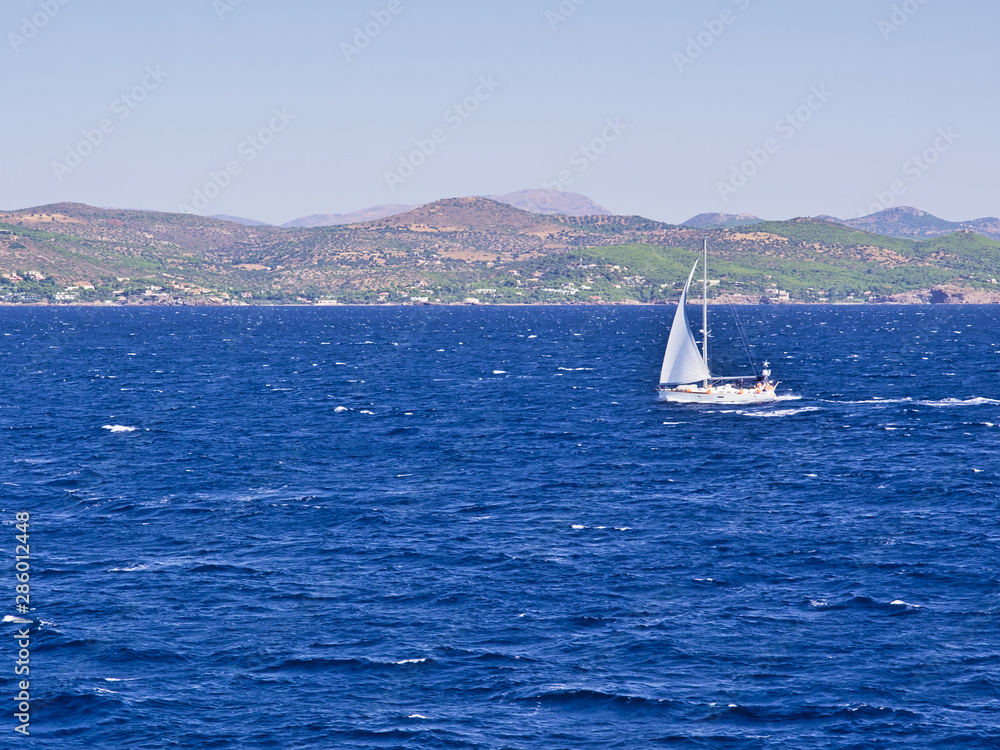 Sailboat at Aegean sea, background with island hills.