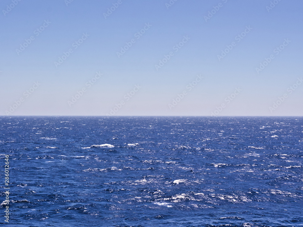 Wavy deep blue sea and sky. Horizon line in the middle of the frame. Wavy deep blue sea and sky. Horizon line in the middle of the frame.