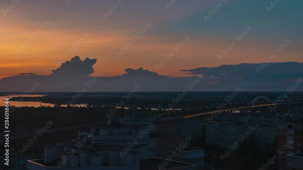 Clouds floating in sunset sky aerial view from drone. Timelapse colorful evening sky over modern city. Cars driving on bridge over river Volga on urban architecture landscape Clouds floating in sunset sky aerial view from drone. Timelapse colorful evening sky over modern city. Cars driving on bridge over river Volga on urban architecture landscape