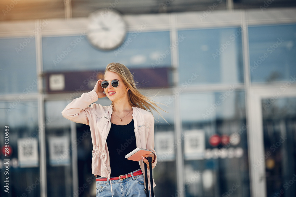 Fototapeta premium Girl in a airport. Blonde with a documents. Lady in a black t-shirt