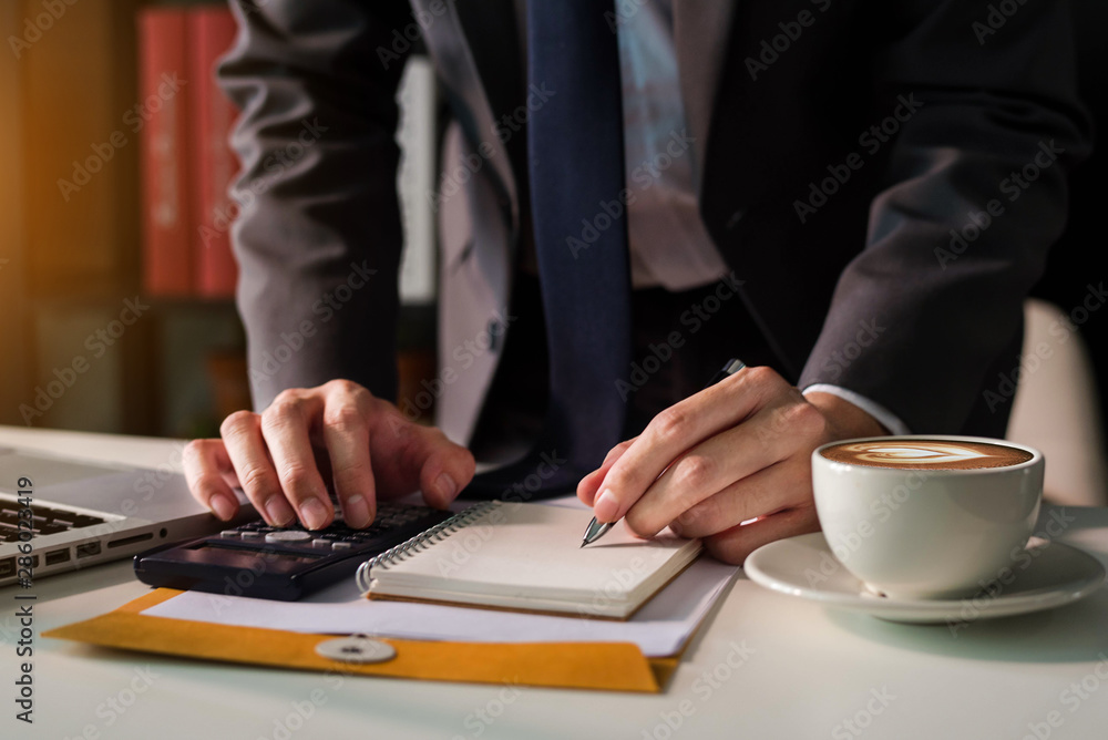 Male businessman working on desk office with using a calculator to calculate the numbers, finance accounting concept. Male businessman working on desk office with using a calculator to calculate the numbers, finance accounting concept.