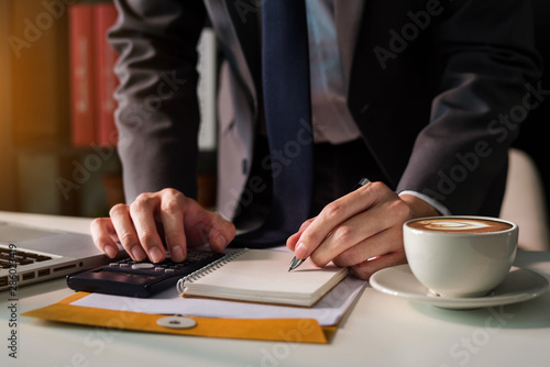 Male businessman working on desk office with using a calculator to calculate the numbers, finance accounting concept.