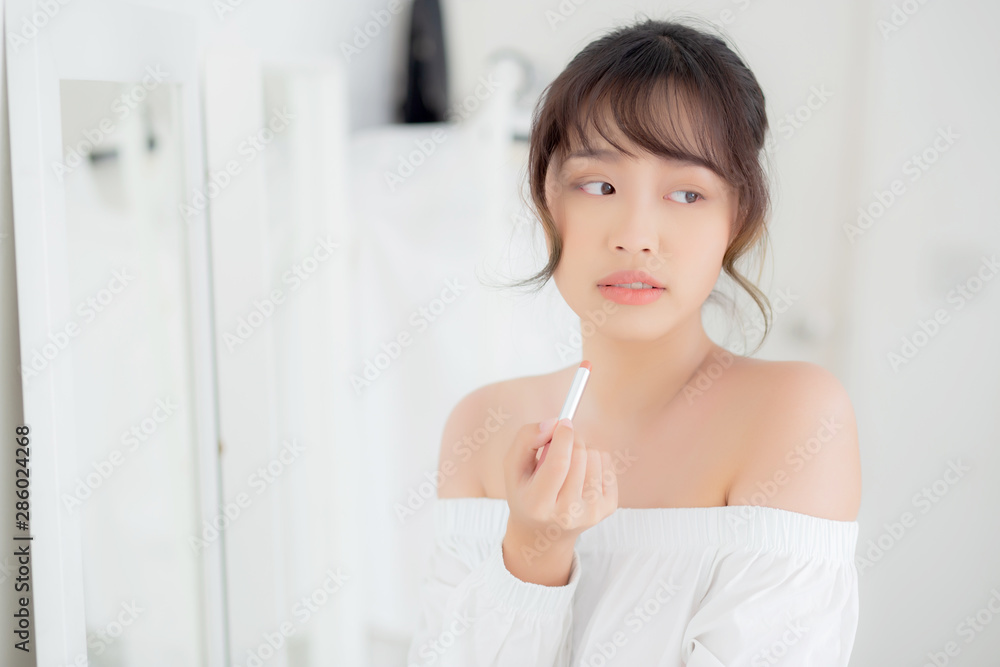 Beautiful portrait young asian woman looking mirror applying makeup lipstick at room, beauty lips asia girl makeup and cosmetic fashion on mouth at home, lifestyle and health care concept. Beautiful portrait young asian woman looking mirror applying makeup lipstick at room, beauty lips asia girl makeup and cosmetic fashion on mouth at home, lifestyle and health care concept.