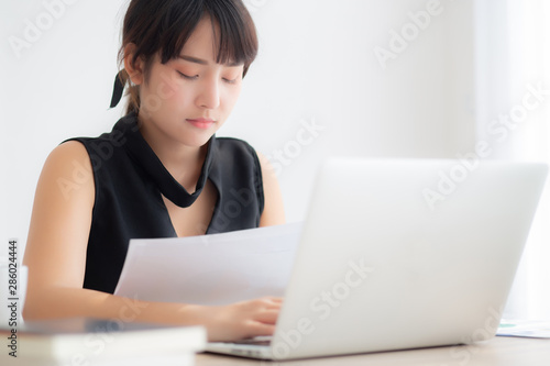 Beautiful young asian woman working with laptop computer at office, businesswoman looking graph diagram analysis statistic data of finance, girl using notebook, profit growth, business concept. © N_studio
