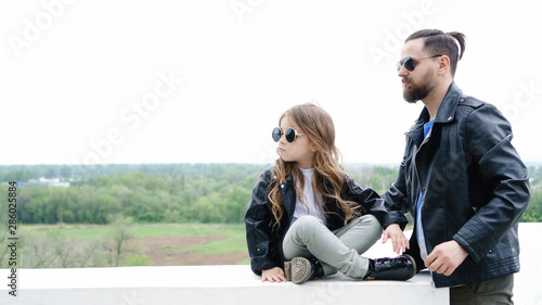 Fashionable stylish family for a walk. Charming schoolchild and her handsome young dad spend time together outdoors. Family look. Urban casual outfit. Muted tones photo