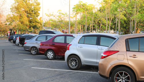 Closeup of rear or back side of pink-gold car with other cars parking in outdoor parking lot with natural background in twilight evening. 