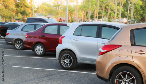 Closeup of rear or back side of pink-gold  car with  other cars parking in outdoor parking lot with natural background in twilight evening. 