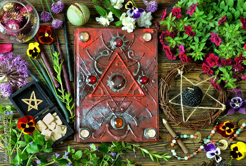 Still life with magical book, healing crystals, runes and herbs on witch table.