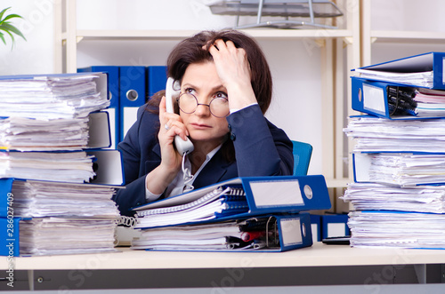 Middle-aged businesswoman unhappy with excessive work photo