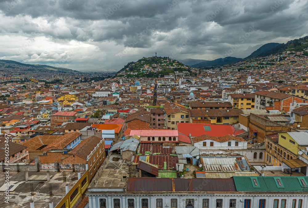 Cityscape of Quito with a dark dramatic sky with the historic city center, the panecillo hill with the Virgin of Quito on top and the Andes mountain range, Ecuador, South America.