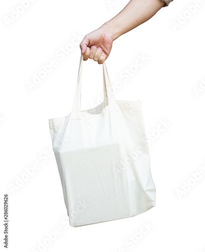 male hand is carrying a white cloth bag to help with the use of plastic bags to reduce global warming.