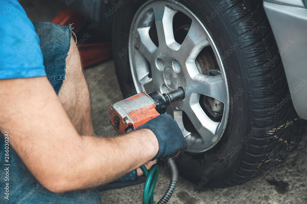 Fototapeta premium car mechanic screwing a car wheel