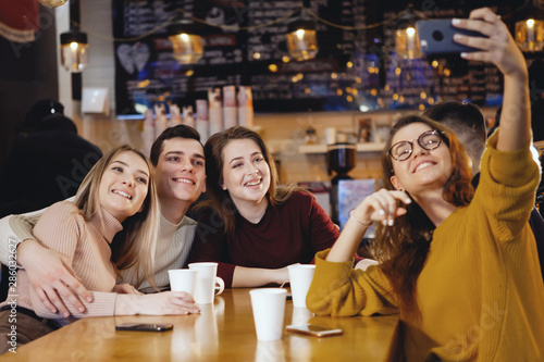Five young handsome students sitting in a cafe.