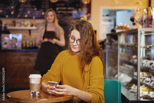 Young pretty woman and waitress in cafe.