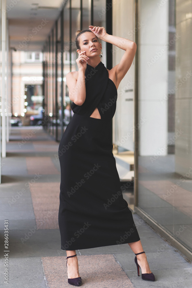 black evening womens dress on beautiful slender European model. Posing on street black evening womens dress on beautiful slender European model. Posing on street