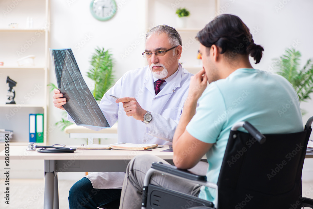 Male patient in wheel-chair visiting old doctor Male patient in wheel-chair visiting old doctor