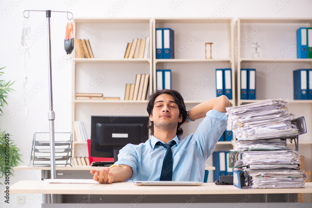 Young male employee in blood transfusion concept Young male employee in blood transfusion concept