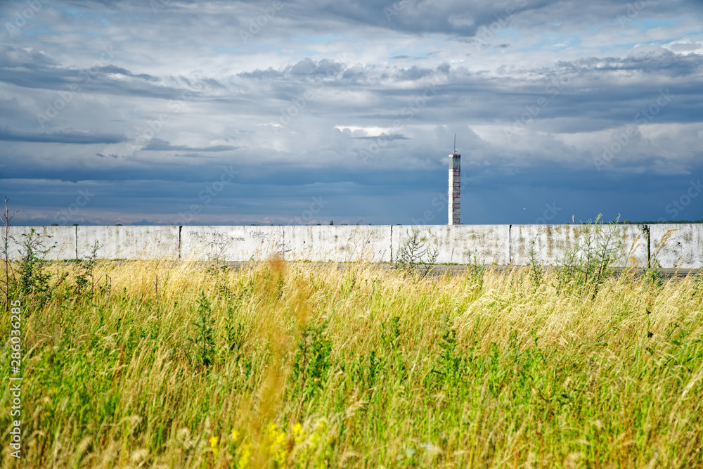 Fototapeta premium Lighthouse or old beacon under storm clouds against yellow field