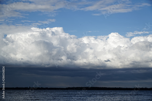 Storm cloud and lighthouse. Dramatic cloudscape texture. Dark heavy thunderstorm clouds before rain. Overcast rainy bad weather. Storm warning. Natural blue background of cumulonimbus