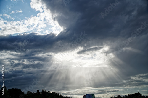 Rays of bright sun peep out from behind dark clouds, sun break after storm