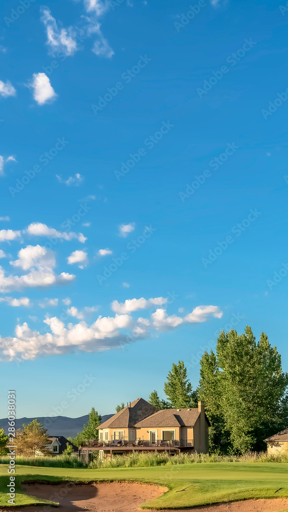 Vertical Bunker and fairway of a golf course viewed under cloudy blue sky on a sunny day