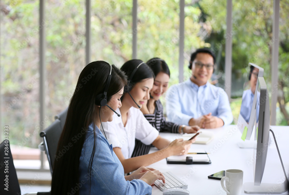 Portrait of smiling businesswoman with headset at computer in office 