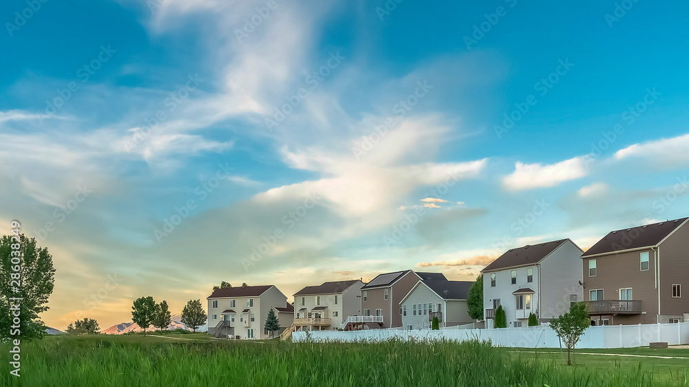 Panorama Expansive terrain covered with rich green grasses in front of family homes Panorama Expansive terrain covered with rich green grasses in front of family homes