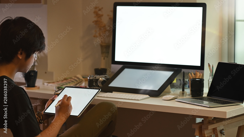 Graphic designer working on creative studio, Man's hand drawing on tablet with pen.