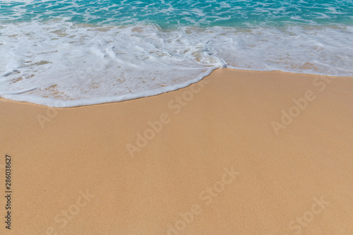 Sandy beach background with ocean wave white foam.