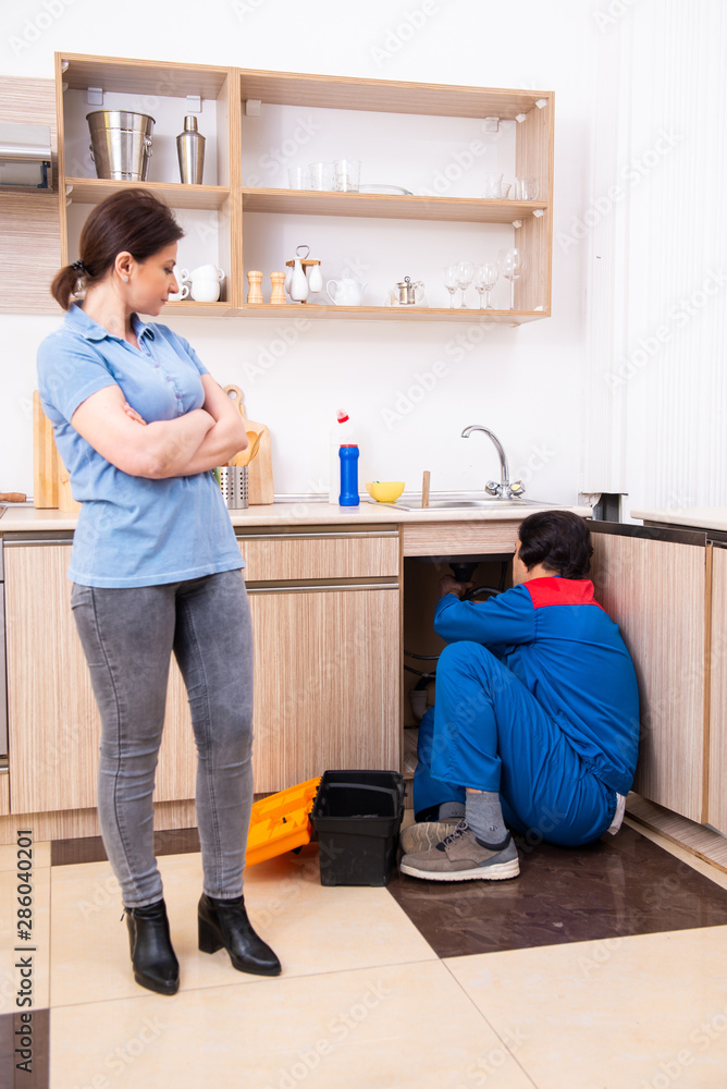 Young male repairman repairing tap Young male repairman repairing tap