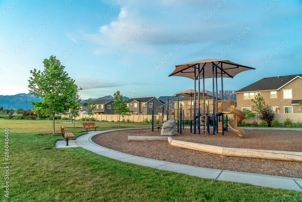 Neighborhood park with benches and pathway around a childrens playground Neighborhood park with benches and pathway around a childrens playground