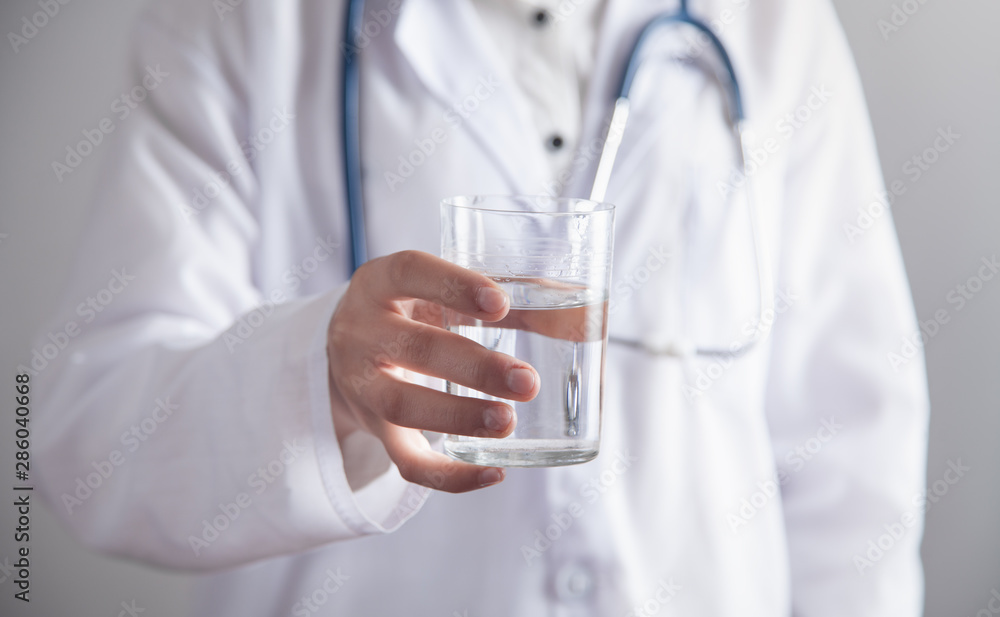 Medical doctor holds glass of water. Medical doctor holds glass of water.