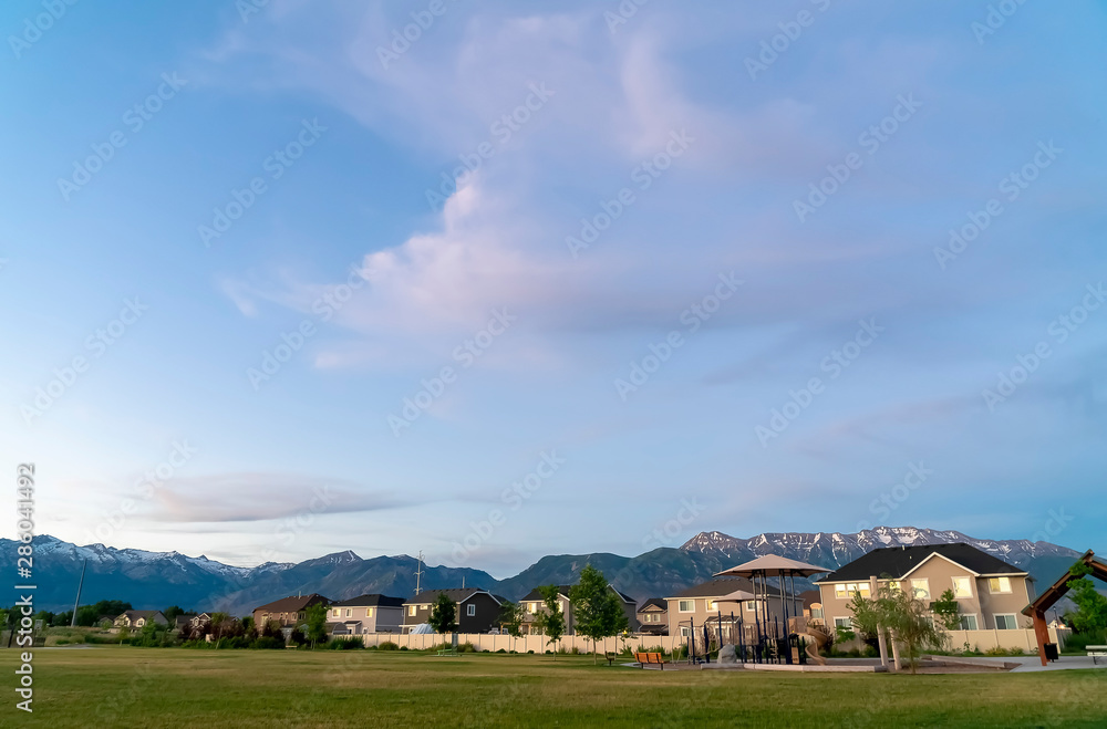 Scenic view of a neighborhood with towering mountain and cloudy sky background
