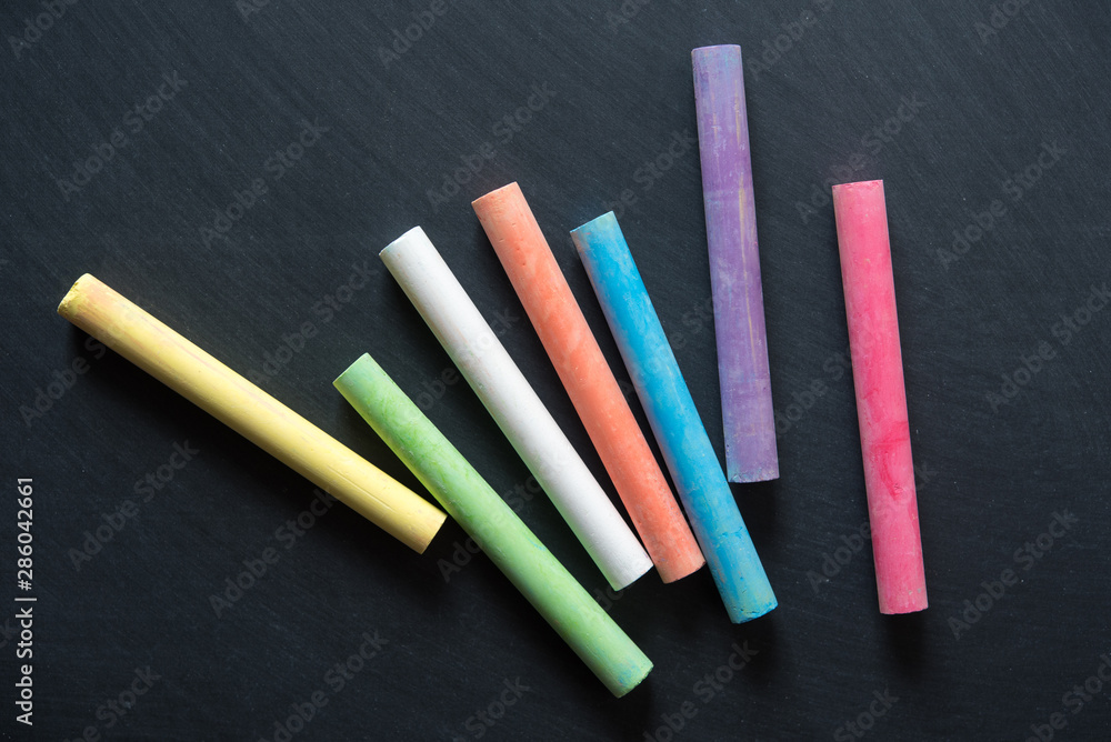 multicolor chalk stick on black chalkboard background multicolor chalk stick on black chalkboard background