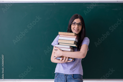Young female teacher student in front of green board © Elnur