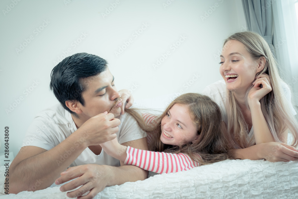 little girl smiling with mother and father on bed together in bedroom at home, young happy family concept little girl smiling with mother and father on bed together in bedroom at home, young happy family concept