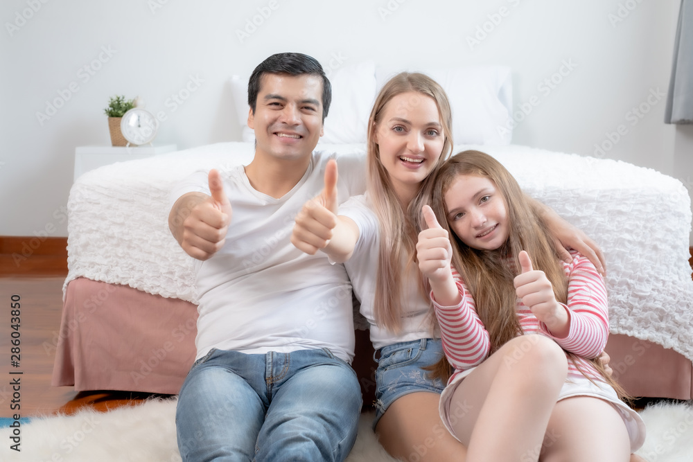 little girl with mother and father, happy family thumb up together and smiling in front of bed together in bedroom at home, young happy family concept little girl with mother and father, happy family thumb up together and smiling in front of bed together in bedroom at home, young happy family concept