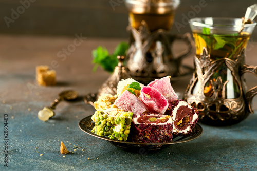Fototapeta Naklejka Na Ścianę i Meble -  Traditional turkish tea with mint leaves and sweets in a traditional glass on a concrete background