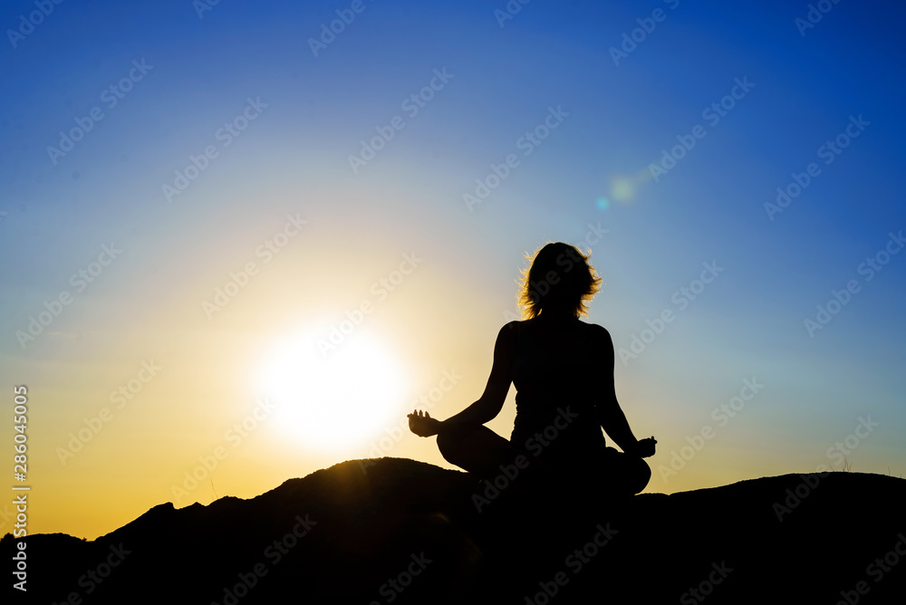 Silhouette Asia woman yoga on the beach at sunset.