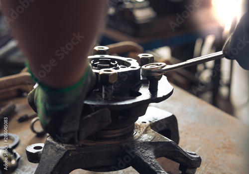 Hands of mechanical engineer using hand tool wrench to fix metal auto parts in garage after accident - insurance, workshop and automotive repair concept