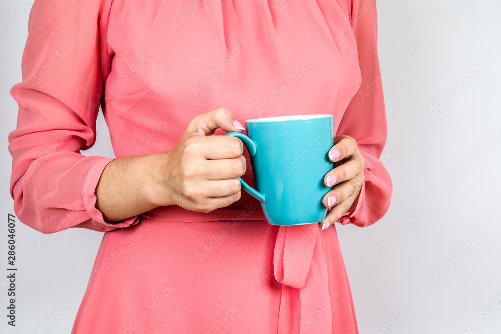 Close-up of a woman's hand holding a cup of hot coffee. Pink nails and dress Close-up of a woman's hand holding a cup of hot coffee. Pink nails and dress