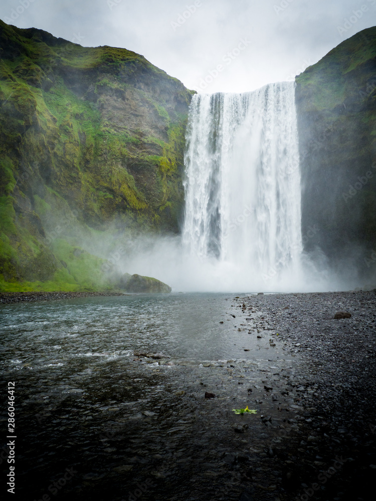 Obraz premium Skogafoss waterfall in green mountain landscape in Iceland