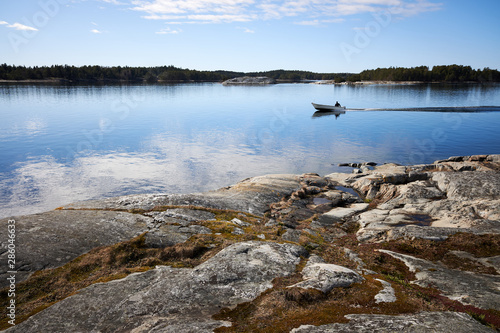Small fishing boat on still sea water. Beautiful rocks on the shore of th Baltic Sea in Kassnäs, Kemiö island in Finland. © Teemu Tretjakov