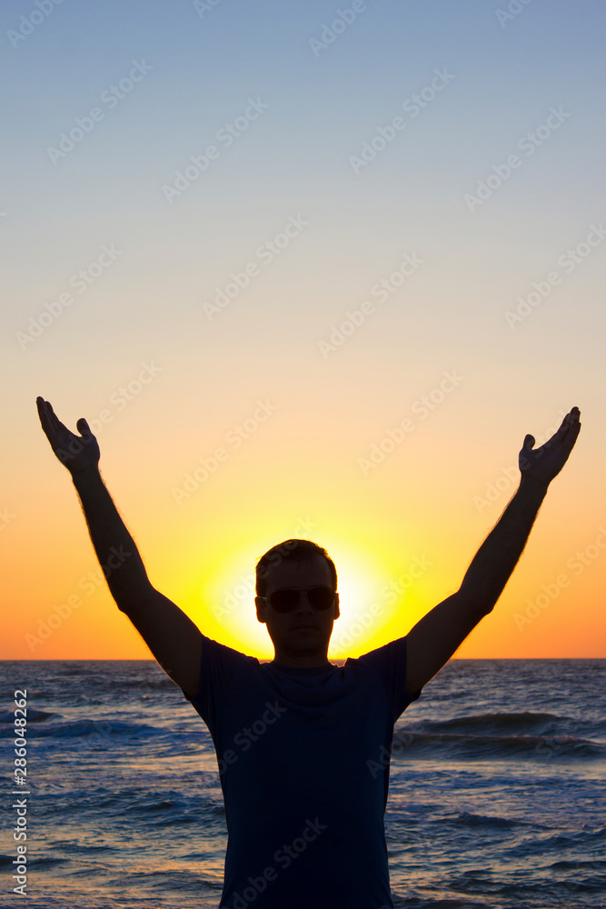 Young man hands up sunrise background blue sky and sea