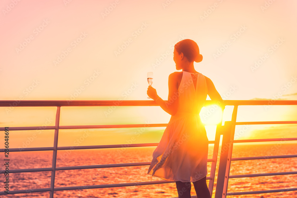 Luxury cruise ship travel elegant woman drinking glass of champagne enjoying watching sunset from boat deck over ocean in Europe destination vacation. Cruising sailing away on holiday. - obrazy, fototapety, plakaty 