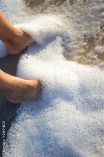 Feet young man on sand sunrise background sea  beach wave