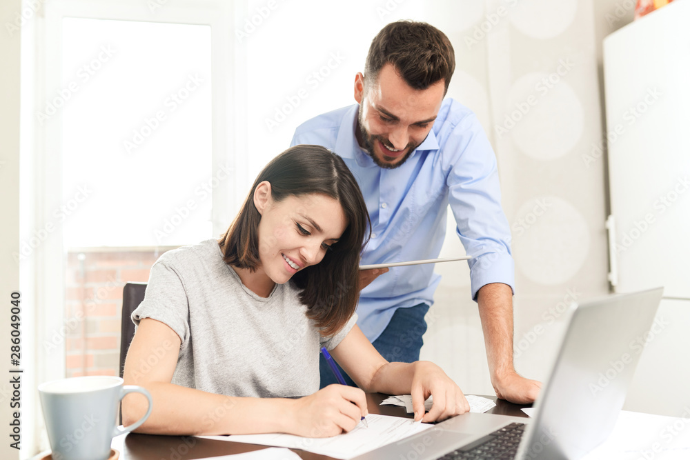 Content confident young man using tablet app while assisting girlfriend Content confident young man using tablet app while assisting girlfriend